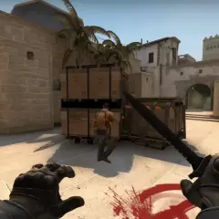 Gracz w Counter-Strike 2 z nożem w ręku, gotowy do ataku na przeciwnika w pustynnej lokacji.